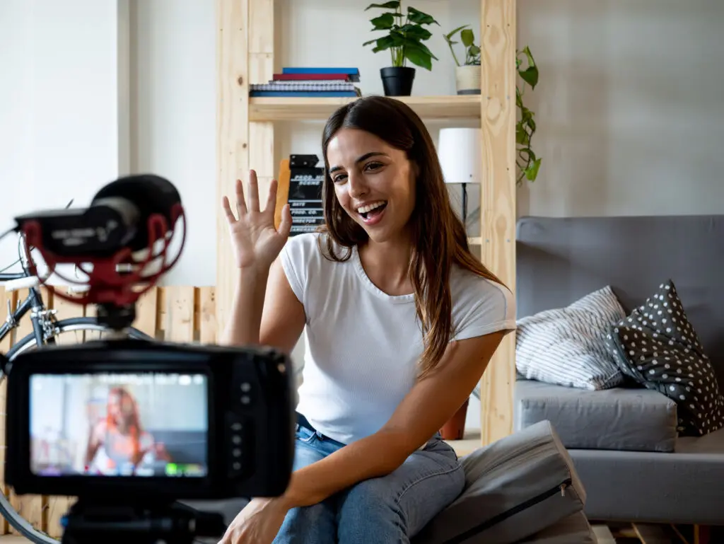 Young woman recording a video for social media with a camera in an apartment.