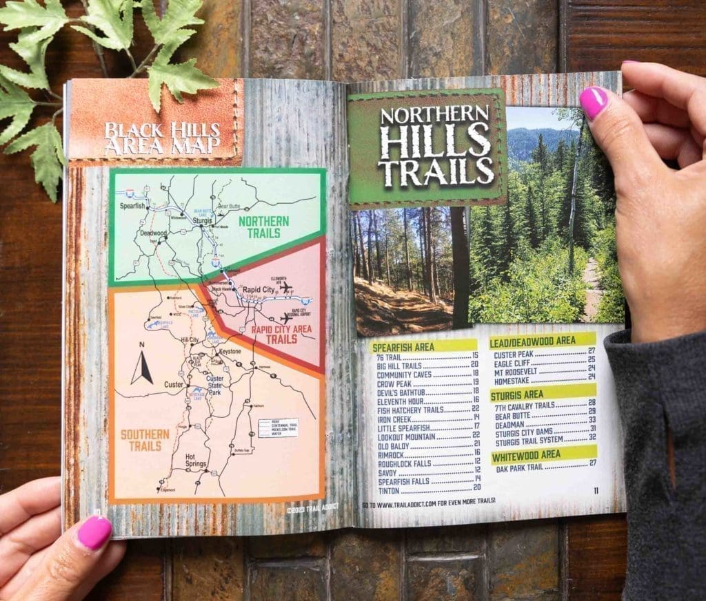 Women holding magazine displaying hiking trails found in the Northern parts of the Black Hills in South Dakota.