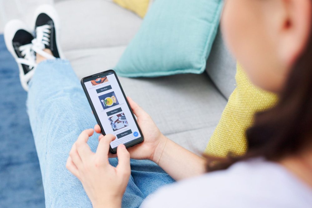 Woman, hands and browsing phone screen on homepage, website or mobile app for ecommerce on living r.